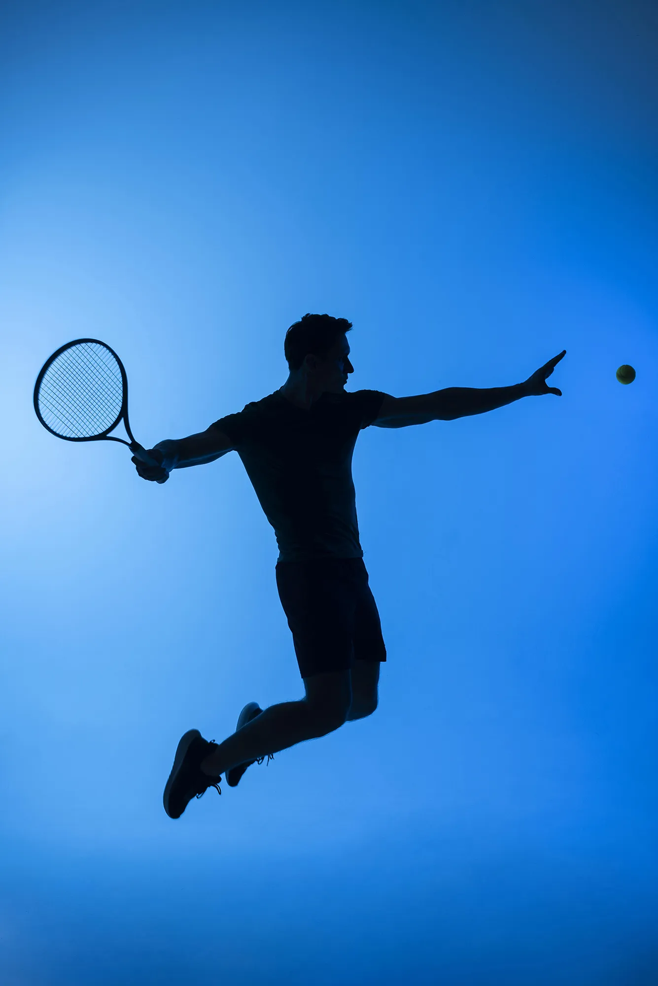 La silhouette di un tennista in salto pronto a colpire una palla da tennis, su uno sfondo azzurro